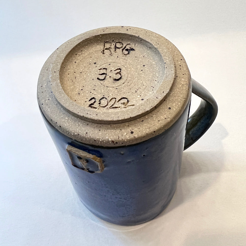 photo of the bottom of a handmade pottery mug for the round pond getaway at moxie cove with blue glaze