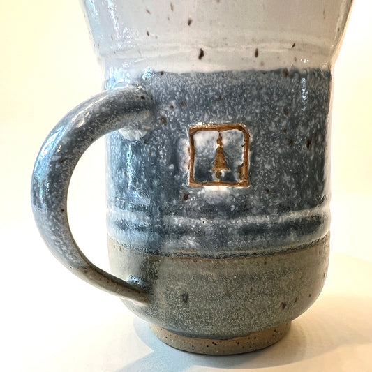 close up photo of handmade pottery mug for the round pond getaway, with white, blue and grey glazes